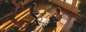 a serene mediation room bathed in soft natural light, where two parents are engaged in a constructive dialogue across a warm wooden table, embodying collaboration and hope for a positive resolution in their parenting dispute.